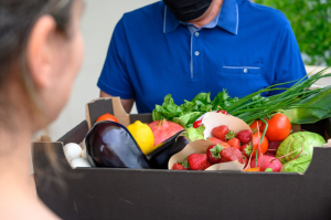 delivery-man-wearing-face-mask-holding-box-with-vegetables_1268-14610